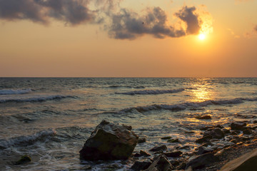Wall Mural - seascape sunset the sun sets the sea wave the sea foam. stones coast