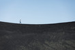 © Cavan Images - woman walks alone on a black basalt sand concave horizon line