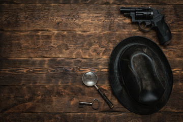Wall Mural - detective or spy agent wooden table flat lay background with copy space. handgun, black leather hat,