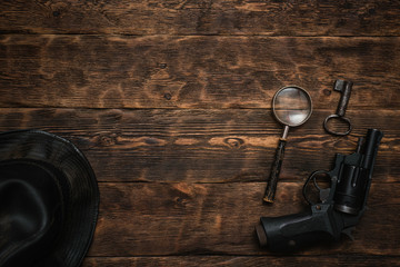 Wall Mural - detective or spy agent wooden table flat lay background with copy space. handgun, black leather hat,