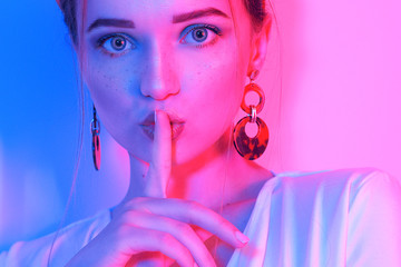 Wall Mural - Fashion portrait of young elegant girl in a white dress. Sensual beautiful brunette, long hair. Leopard print accessories. Woman in the earrings and headband. The girl shows a gesture of silence.