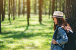 © Farknot Architect - An asian female traveler with a hat and backpack looking into a beautiful pine woods