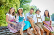 © karepa - Freunde in bayerischen Tracht feiern an der Isar und trinken Bier. Oktoberfest München