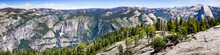 Panoramic View In Yosemite National Park With Yosemite Falls On The Right And Half Dome On The Left; Snow Covered Peaks Visible In The Background; Sierra Nevada Mountains, California