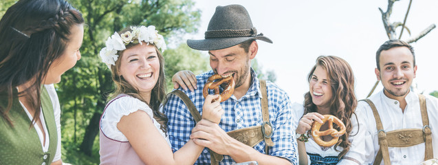 Friends in Bavarian costume celebrate on the river Isar and drink beer. Oktoberfest munich