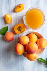 Wall Mural - Ripe apricots and glass of apricot juice on blue rustic background with copy space. Selective focus. Eco food concept. Fresh summer drinks. Detox. Non alcoholic. Vertical. Top view