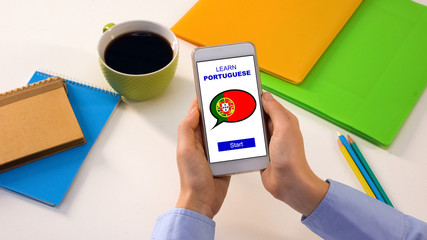 Learn Portuguese application on cellphone in persons hands, studying language