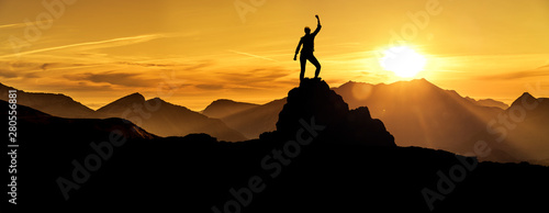Fotografía Frau in Siegerpose bei Sonnenaufgang auf einem Berggipfel