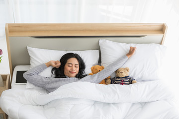 Woman lying in bed and looking over the blanket..