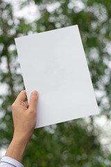 Woman holding paper blank of drawing paper paper with natural background.