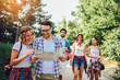 © Mediteraneo - Group of smiling friends walking with backpacks in woods - adventure, travel, tourism, hike and people concept