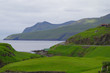 Panoramablick über grüne Wiesen bei Leynar auf der Färöer-insel Streymoy mit Felsen und Bergen der Insel Varga im Hintergrund