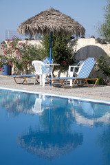 Wall Mural - Sunbeds, Umbrella and table at the board of a idyllic swimming pool