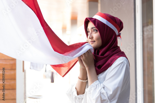 Fotomural portrait of young asian woman with scarf kissing red and white flag of indonesia