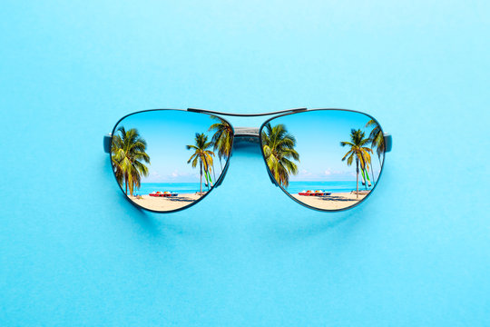 Wall Mural -  - Summer vacation concept. Sunglasses with ocean beach and palms on blue background.