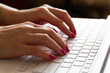 © marketlan - Hands of a girl typing on a white laptop keyboard. Closeup