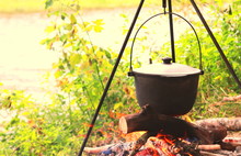 Cooking Delicious Tasty Food Outdoors On Fire In Iron Pot In Summer In Good Weather With Wood From Forest