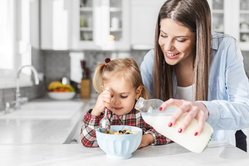 Shot of pretty young mother and her daughter preparing breakfast in the kitchen at home