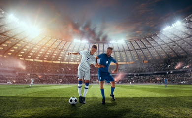 Soccer players in action on professional stadium on sunset.