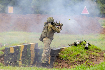 A soldier shoots a jet flame thrower into the field.