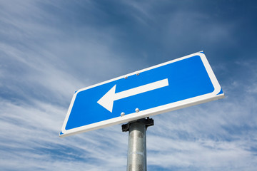 traffic sign arrow pointing left against sky