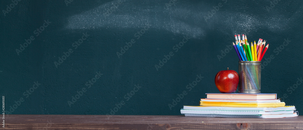 Pencil tray and an apple on notebooks on school teacher's desk. - obrazy, fototapety, plakaty 