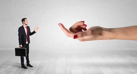 Businessman with kisses on his face in an empty space where a big hand baiting him