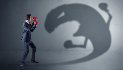 Wall Mural - Businessman with boxing glove fighting with a big monster shadow