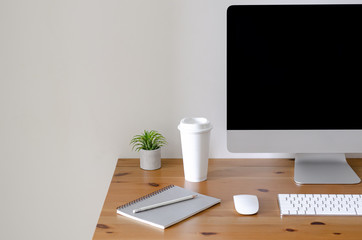 modern personal computer screen on wooden table with a cup of coffee and tillandsia air plant with s