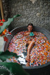 © Yevhenii - Woman relaxing in round outdoor bath with tropical flowers and drinking heral tea. Organic skin care in  in luxury spa resort