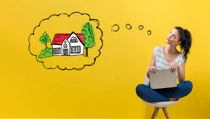 Wall Mural - Dreaming of new home with young woman using a laptop computer