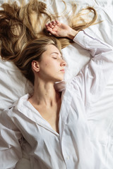 Wall Mural - Portrait beautiful blonde woman with a beautiful face and amazing eyes, lies, sleeps on the bed linen in an elegant. And sensual looks and flirtatious smile. Health and harmony concept