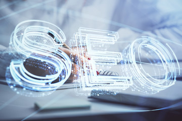 Double exposure of woman's hands making notes with SEO icon. Concept of Search engine optimization