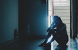 © TeTe Song - Silhouette of girl sitting alone in the dark,Sad and Serious women sitting hug his knee alone of old condo, Domestic violence, family problems, The concept of depression and suicide with copy space