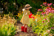 © КРИСТИНА Игумнова - little girl in red rubber boots and a straw hat watering red watering flowers in the garden