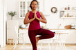 © Anatoliy Karlyuk - Concentrated attractive young dark skinned woman wearing leggings and top doing yoga asanas to develop balance, standing at home in tree pose, keeping hands in front of her, showing namaste