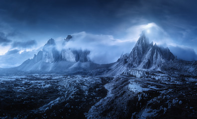 Wall Mural - mountains in fog at beautiful night. dreamy landscape with mountain peaks, stones, grass, blue sky w