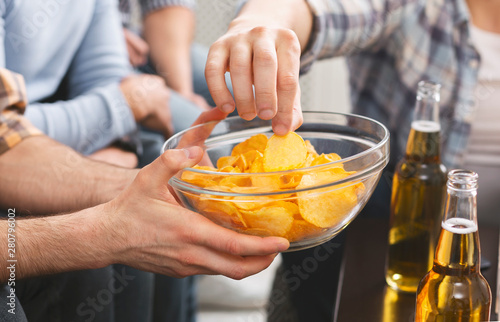 Fotografía Man holding bowl with chips sharing with friends at party