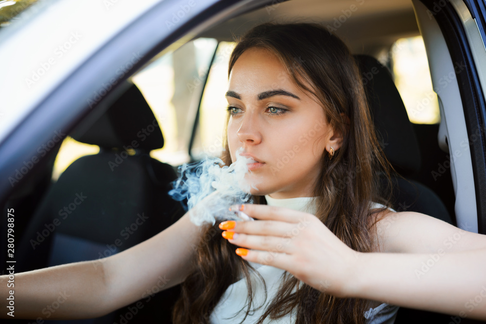 driving and smoking cigarettes Young attractive girl smoking cigarette with a lot of smoke while driving a  car Stock Photo