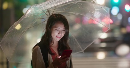 Canvas Print - Woman hold with umbrella and use of mobile phone in the city at night