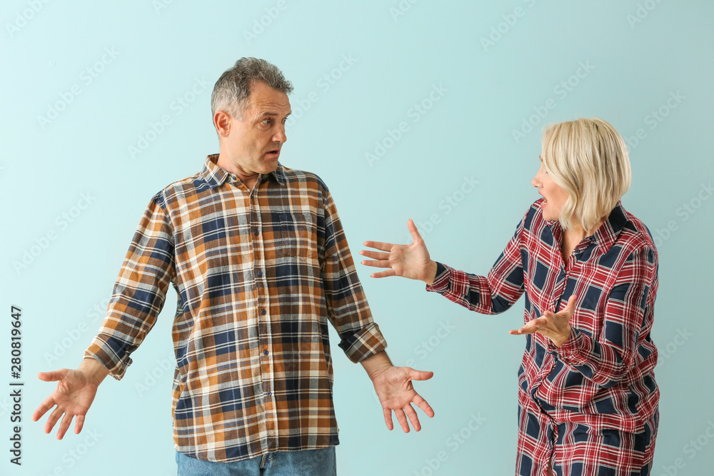 Quarrelling middle-aged couple on color background