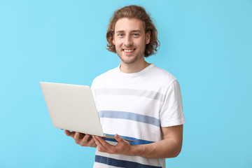 Male programmer with laptop on color background