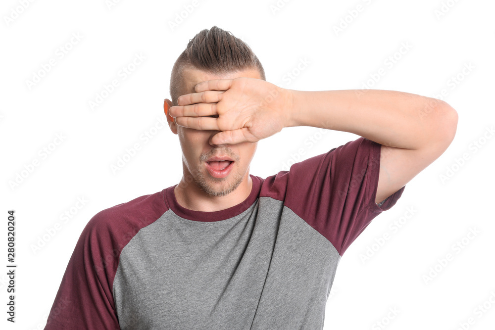 Young man covering his eyes on white background