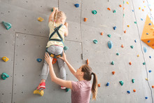 Instructor Helping Little Girl To Climb Wall In Gym
