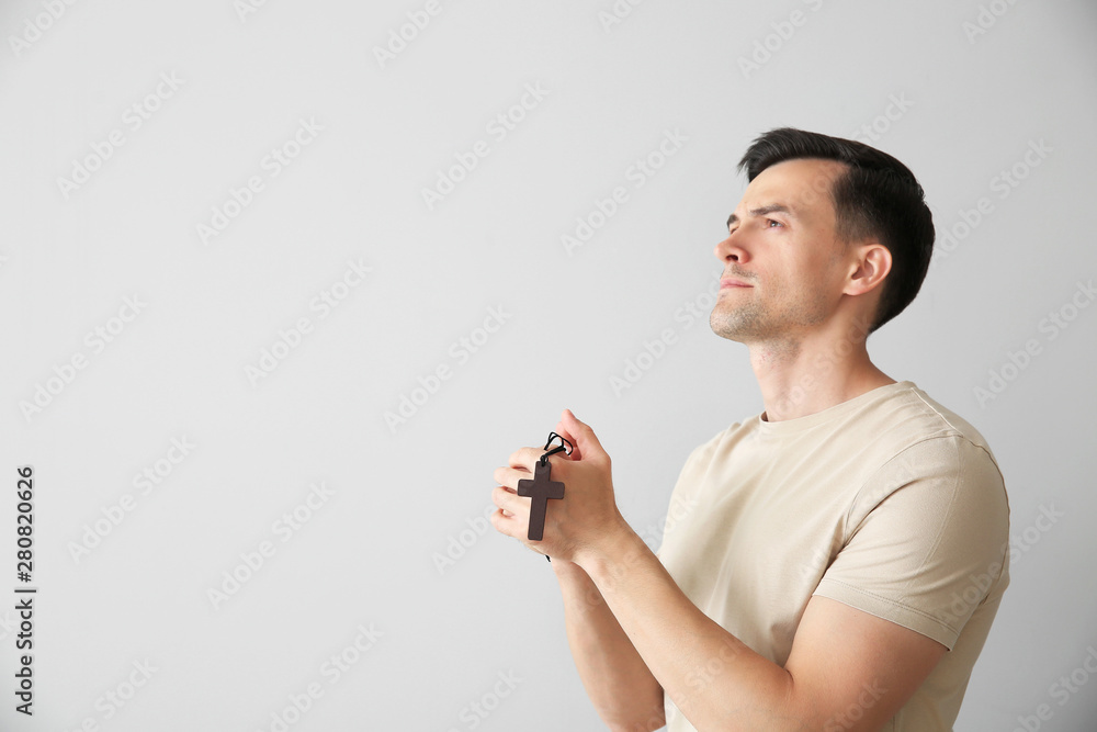 Religious man praying to God on light background
