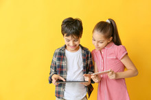 Cute Little Children With Tablet Computer And Mobile Phone On Color Background