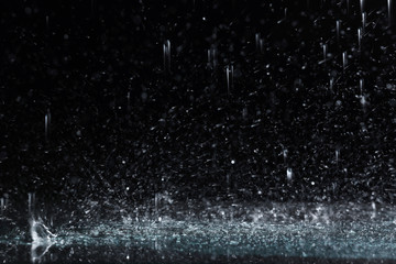 heavy rain falling down on ground against dark background
