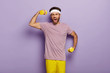 © wayhome.studio  - Motivated guy trains muscles on hands, lifts dumbbells, shakes biceps, wears sportwear, wants to have athletic body, yells something, stands against violet background. Good exercise for training