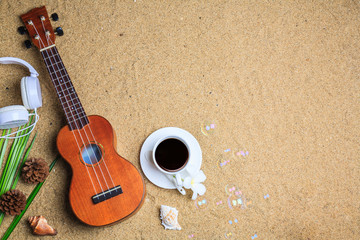 Ukulele with note paper,Coffee,Headphones and seashell on the beach