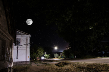 Wall Mural - full moon over quite village at night. beautiful night landscape of old town street with lights. rus